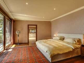 Experience luxurious living in this spacious bedroom featuring a king-sized bed with plush bedding and a striking accent rug.