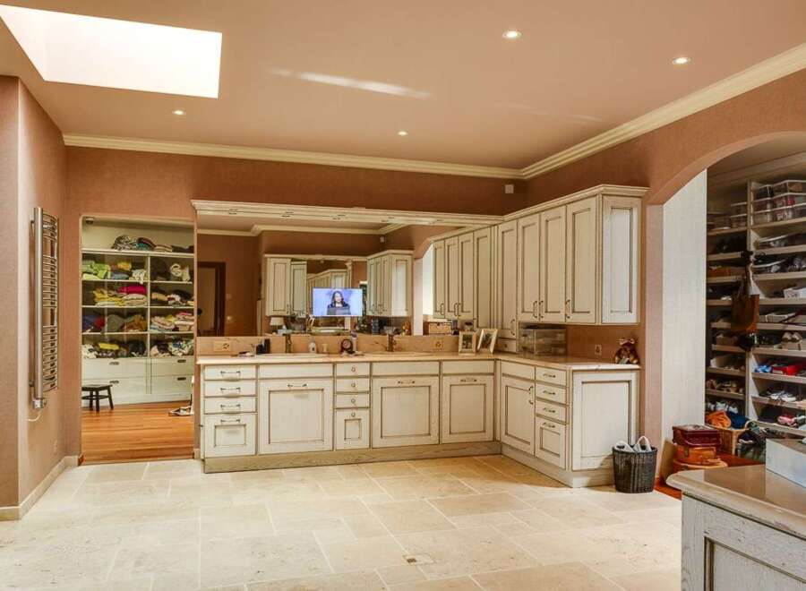 Discover this expansive walk-in closet and dressing room, featuring custom cabinetry and ample shelving for organized storage.