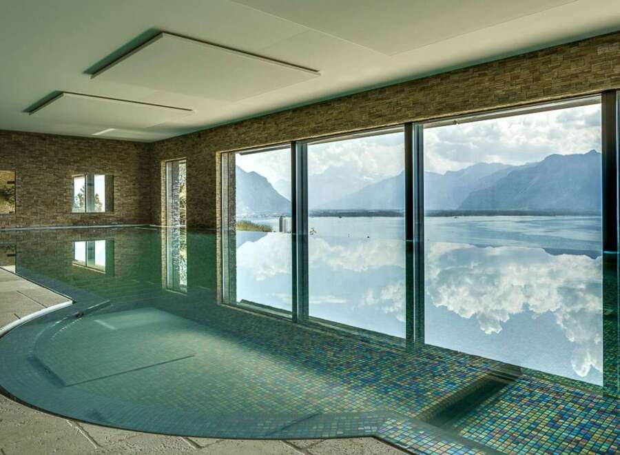 Experience luxury living with this stunning indoor swimming pool, featuring breathtaking panoramic views of majestic mountains and a serene lake.