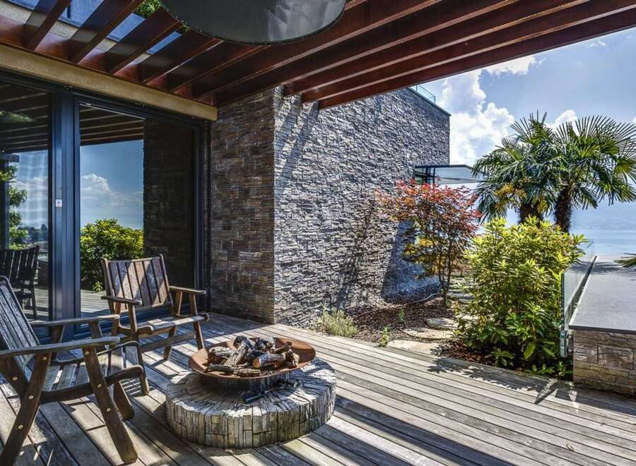 Experience luxurious outdoor living with this stunning deck featuring comfortable seating and a rustic fire pit, perfect for evening gatherings.