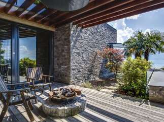 Experience luxurious outdoor living with this stunning deck featuring comfortable seating and a rustic fire pit, perfect for evening gatherings.