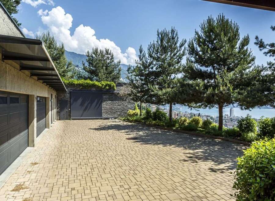 Experience luxury living with this stunning property featuring a spacious driveway leading to multiple garage doors.