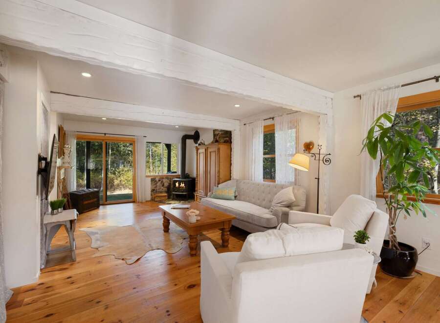 Experience rustic charm in this inviting living room, featuring exposed wooden beams and a cozy wood-burning stove.