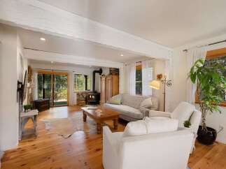 Experience rustic charm in this inviting living room, featuring exposed wooden beams and a cozy wood-burning stove.