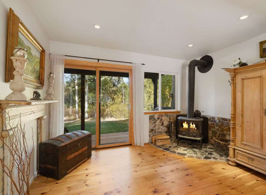 Cozy living room featuring a rustic wood-burning stove set against a stone hearth, perfect for chilly evenings.