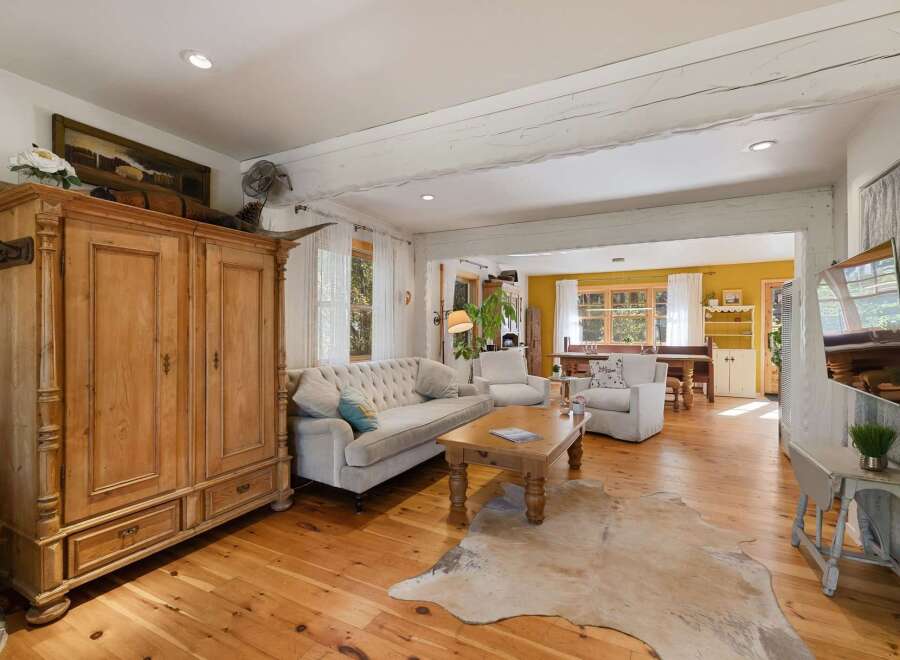Experience rustic charm in this inviting living space, featuring a large wooden armoire and a plush tufted sofa perfect for relaxation.
