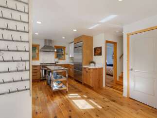 This charming kitchen boasts a professional-grade stainless steel range and hood, complemented by warm wooden cabinetry and sleek marble countertops.