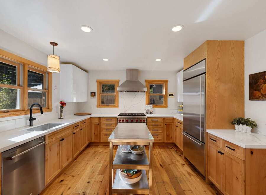 This beautifully remodeled kitchen features warm, natural wood cabinetry complemented by sleek white countertops and a striking marble backsplash.