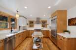 This beautifully remodeled kitchen features warm, natural wood cabinetry complemented by sleek white countertops and a striking marble backsplash.