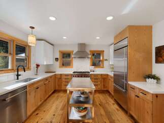 This beautifully remodeled kitchen features warm, natural wood cabinetry complemented by sleek white countertops and a striking marble backsplash.