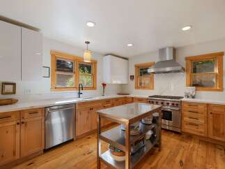 Experience culinary excellence in this stunning kitchen, featuring sleek white cabinetry and warm, natural wood lower cabinets.
