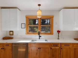This modern kitchen features sleek white upper cabinets contrasted with warm, natural wood lower cabinets and drawers.