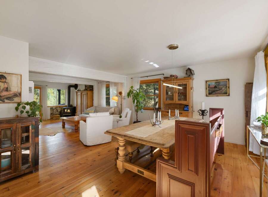 Experience rustic charm in this inviting open-concept living and dining area, featuring a cozy wood-burning stove and abundant natural light.