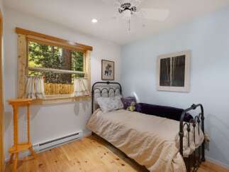 This charming bedroom features a cozy twin bed with a light beige duvet and decorative pillows, perfect for a restful night's sleep.