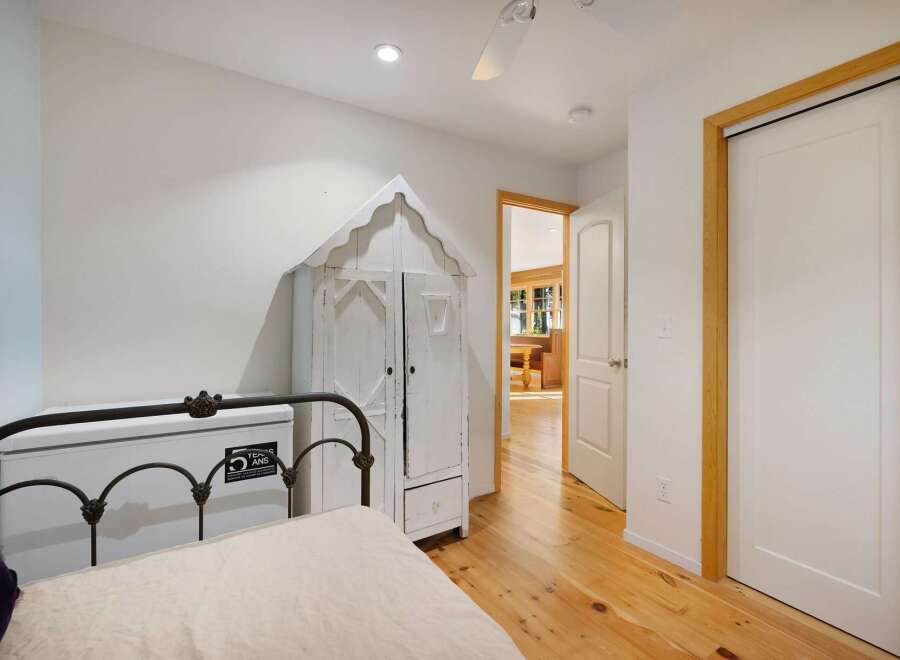 Discover this charming bedroom featuring a unique white distressed armoire and a classic metal-frame bed.