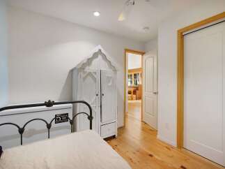 Discover this charming bedroom featuring a unique white distressed armoire and a classic metal-frame bed.