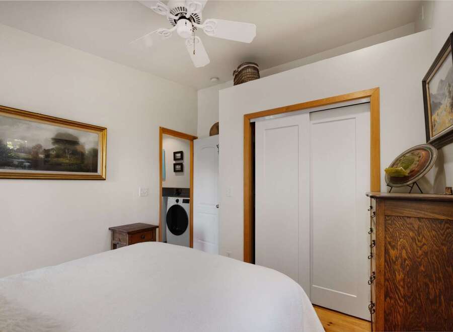 Discover comfort and convenience in this charming bedroom, featuring a plush bed and a functional laundry area discreetly placed behind a doorway.