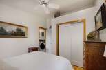 Discover comfort and convenience in this charming bedroom, featuring a plush bed and a functional laundry area discreetly placed behind a doorway.