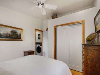 Discover comfort and convenience in this charming bedroom, featuring a plush bed and a functional laundry area discreetly placed behind a doorway.