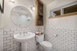 This charming bathroom features a classic subway tile design, a pedestal sink, and a convenient toilet with a decorative basket.