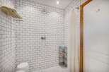 Experience a spa-like retreat in this beautifully tiled shower featuring a rainfall showerhead and a convenient towel rack.
