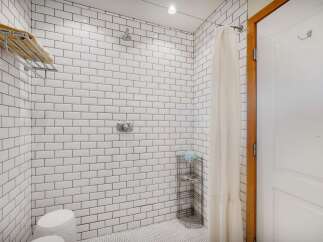 Experience a spa-like retreat in this beautifully tiled shower featuring a rainfall showerhead and a convenient towel rack.