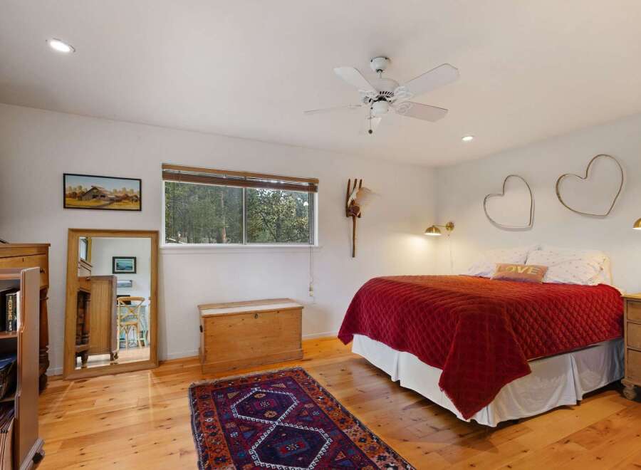 This charming bedroom features a cozy queen-size bed adorned with a vibrant red quilt and a decorative 'LOVE' pillow.