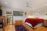 This charming bedroom features a cozy queen-size bed adorned with a vibrant red quilt and a decorative 'LOVE' pillow.