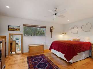 This charming bedroom features a cozy queen-size bed adorned with a vibrant red quilt and a decorative 'LOVE' pillow.