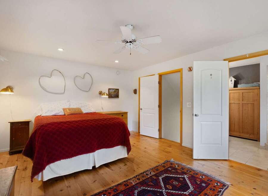 This charming bedroom features a cozy queen-sized bed adorned with a rich red quilted comforter and a decorative 'LOVE' pillow.