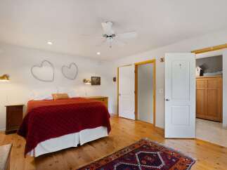This charming bedroom features a cozy queen-sized bed adorned with a rich red quilted comforter and a decorative 'LOVE' pillow.