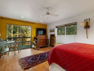 This bedroom offers a serene retreat with a large sliding glass door leading to a private balcony, perfect for enjoying the surrounding nature.