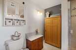This charming bathroom features a white medicine cabinet with mirrored doors and three woven baskets for storage.