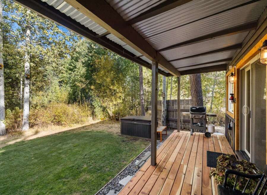 Enjoy outdoor living with this covered deck featuring a grill and a hot tub, perfect for relaxation and entertaining.