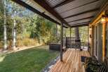 Enjoy outdoor living with this covered deck featuring a grill and a hot tub, perfect for relaxation and entertaining.