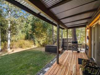 Enjoy outdoor living with this covered deck featuring a grill and a hot tub, perfect for relaxation and entertaining.