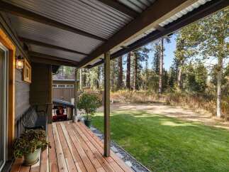 Enjoy the serene outdoors from this charming covered porch, perfect for relaxing with a cup of coffee.