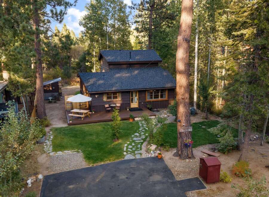 Nestled amidst tall trees, this charming cabin offers a serene retreat with a spacious wooden deck perfect for outdoor dining and relaxation.