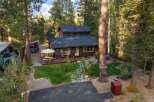 Nestled amidst tall trees, this charming cabin offers a serene retreat with a spacious wooden deck perfect for outdoor dining and relaxation.