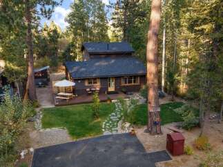 Nestled amidst tall trees, this charming cabin offers a serene retreat with a spacious wooden deck perfect for outdoor dining and relaxation.