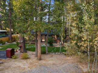 Nestled amidst tall trees, this charming cabin offers a serene retreat with its rustic exterior and inviting porch.