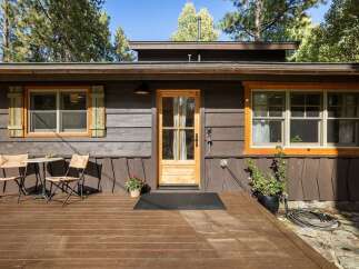 Charming cabin exterior featuring a warm wooden deck, perfect for enjoying the surrounding nature.