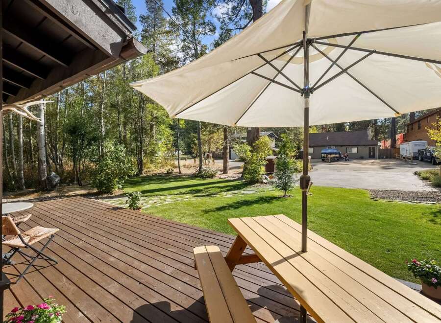 Enjoy outdoor living on this spacious wooden deck, perfect for entertaining or relaxing under the shade of a large umbrella.