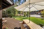 Enjoy outdoor living on this spacious wooden deck, perfect for entertaining or relaxing under the shade of a large umbrella.