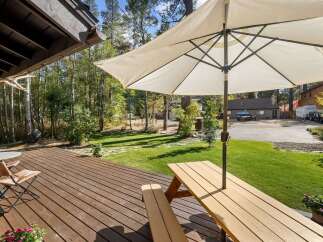 Enjoy outdoor living on this spacious wooden deck, perfect for entertaining or relaxing under the shade of a large umbrella.