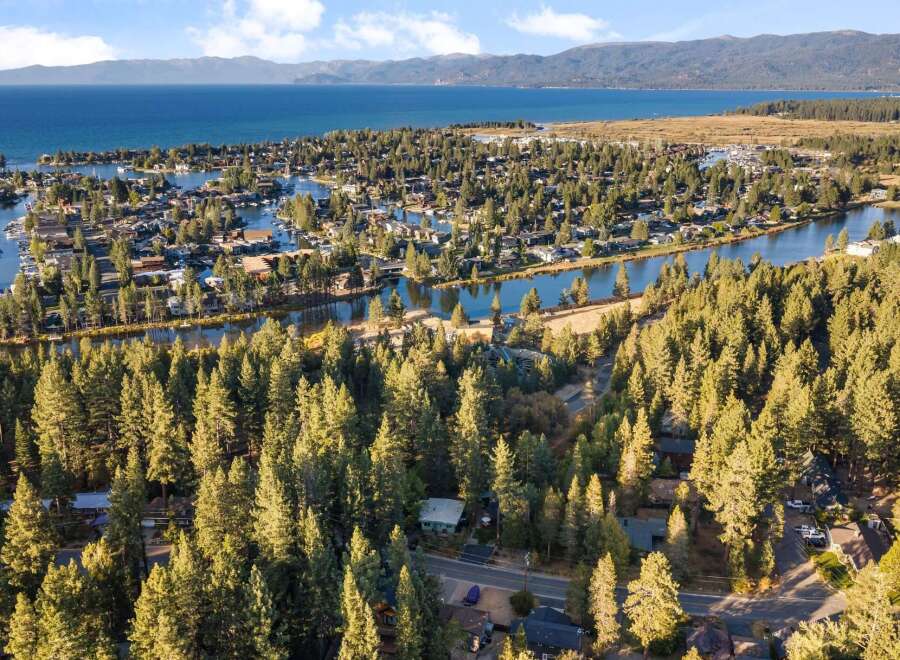 Experience the ultimate lakeside living in this stunning aerial view of a waterfront community nestled amongst lush pine trees.