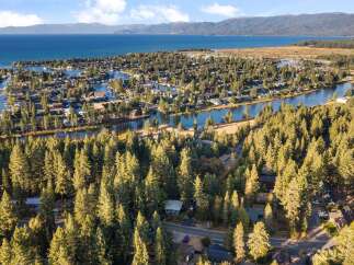 Experience the ultimate lakeside living in this stunning aerial view of a waterfront community nestled amongst lush pine trees.