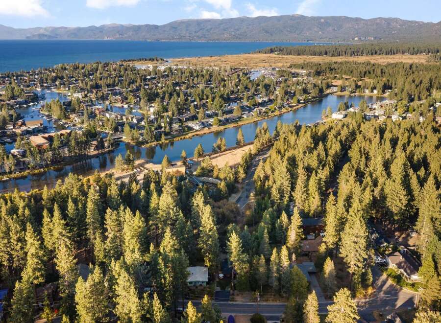 Discover this stunning aerial view of a lakeside community nestled amongst a dense forest of pine trees.