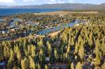 Discover this stunning aerial view of a lakeside community nestled amongst a dense forest of pine trees.