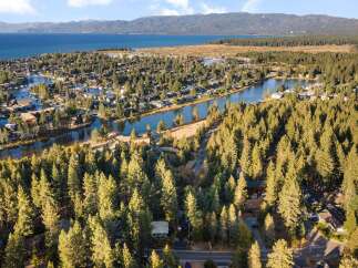 Discover this stunning aerial view of a lakeside community nestled amongst a dense forest of pine trees.